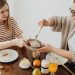 A mother and daughter enjoying a cozy breakfast with toast and juice at the dining table.